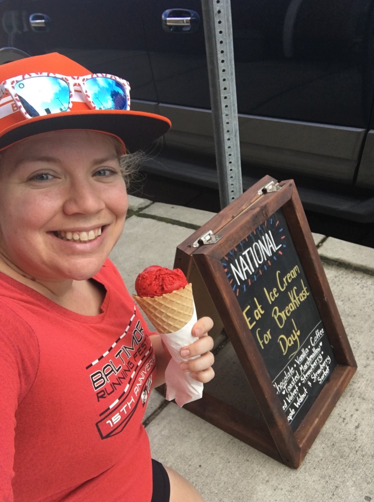 Vanessa Junkin poses with an ice cream cone and a National Eat Ice Cream for Breakfast Day sign. 