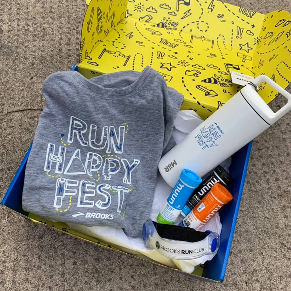 Swag in blue and yellow box, including gray Run Happy Fest shirt, white water bottle, three tubes of Nuun and an armband light.