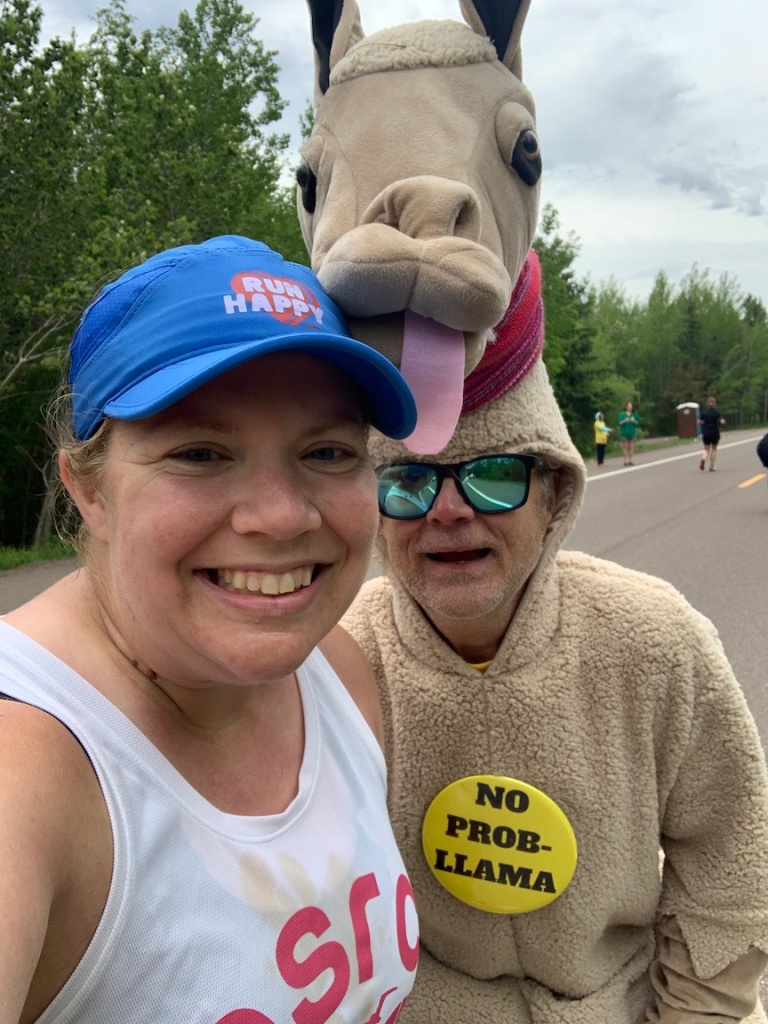 Vanessa Junkin takes a selfie with a man dressed up as a llama. He has a button reading "No Prob-Llama." 