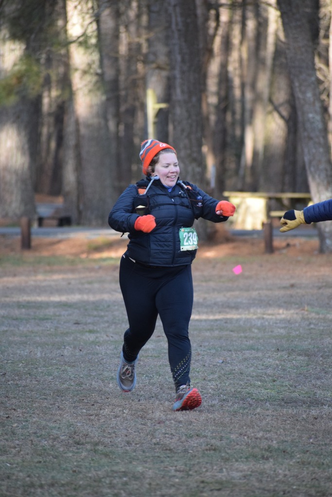 Bundled-up female runner holding fist out for a fist bump, with another fist showing to the right. 
