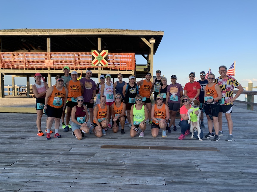Group photo of 22 runners and a dog on a dock. 