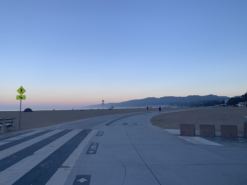 View of path in Santa Monica with the beach to the left and mountains in the distance. 