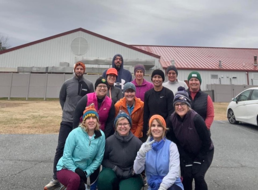 Thirteen runners in winter gear pose for a group photo. 