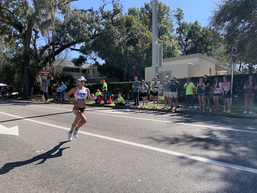 Emily Sisson runs down the street with spectators to the left. 